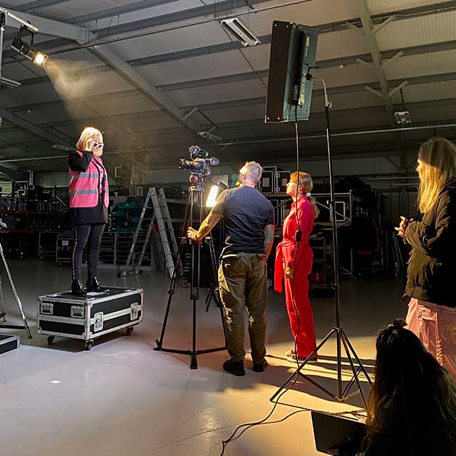 production bureau staff member dressed as barbie for international woman day with professional stage and lighting kit